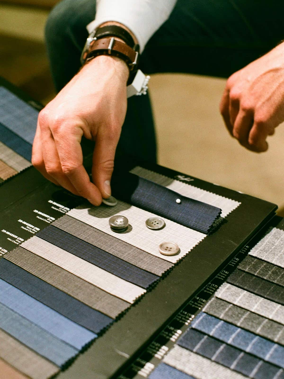 Tailor comparing fabric swatches and buttons for a custom suit